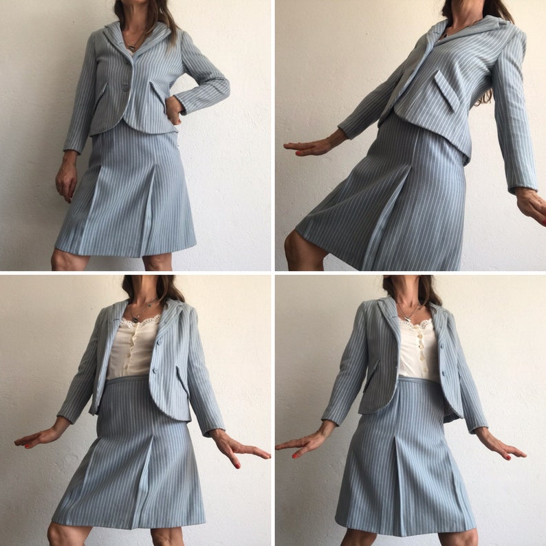 Puede incluir: Un traje de falda azul claro a rayas finas con una chaqueta corta y una falda de l&iacute;nea A. El traje est&aacute; hecho de una tela ligera y tiene un corte cl&aacute;sico y entallado.