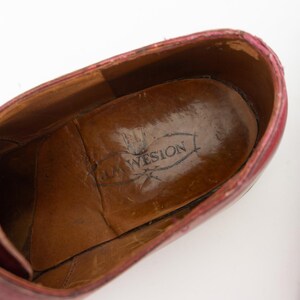 May include: Close-up of the inside of a burgundy leather shoe with a brown leather insole. The insole has the text "Loewsion" printed on it.