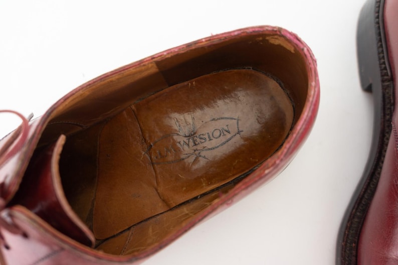 May include: Close-up of the inside of a burgundy leather shoe with a brown leather insole. The insole has the text "Loewsion" printed on it.