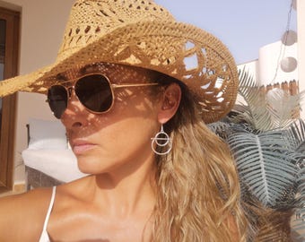 May include: A pair of silver-toned dangle earrings featuring a geometric design composed of a small circle suspended within a larger circle, attached to a simple hook wire. The earrings have a matte finish and a lightweight, open-frame construction.