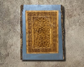 May include: A blue framed wall art piece with a carved wooden design of a geometric pattern in gold. The design is reminiscent of a traditional Islamic archway.
