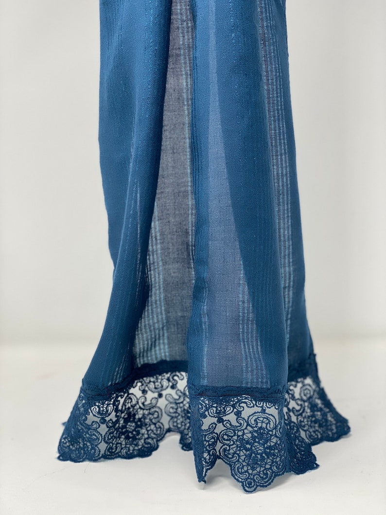 May include: A blue sheer fabric with a lace trim. The fabric has a subtle striped pattern.