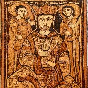 May include: A woodburned image of a king in a crown, seated with two figures standing behind him. The image is in shades of brown and black, with intricate details in the clothing and background.