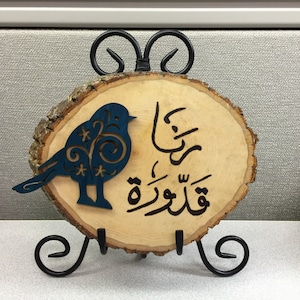 May include: A wooden slice with a blue bird cutout and Arabic calligraphy that reads "قَدْرُكَ عِنْدَ اللَّهِ", which translates to "Your worth is with God".
