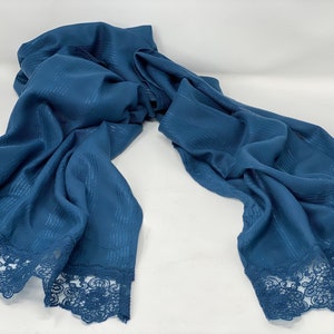 May include: A blue scarf with a lace trim. The scarf has a subtle striped pattern.