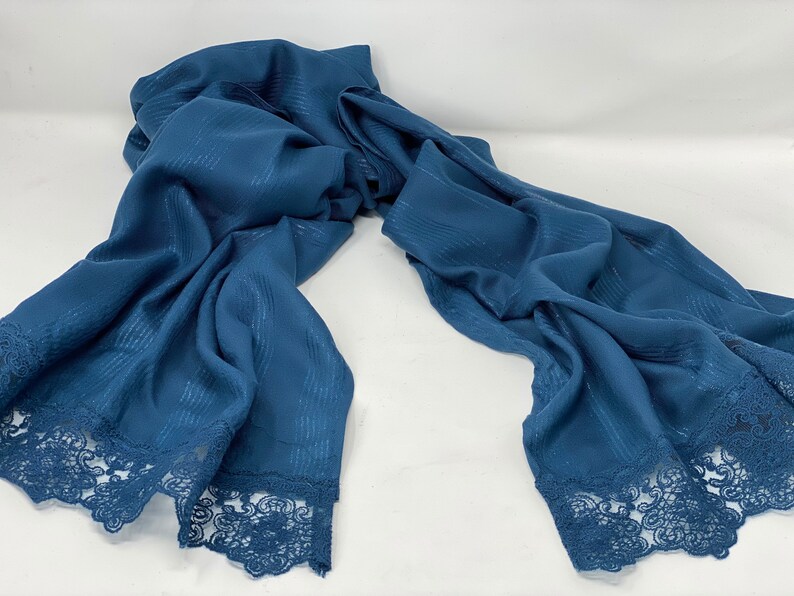 May include: A blue scarf with a lace trim. The scarf has a subtle striped pattern.