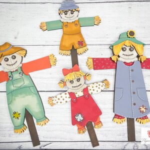May include: Four colorful scarecrow figures with different clothing and hats. The scarecrows are made of paper and have a rustic, whimsical style. They are perfect for fall decorations.