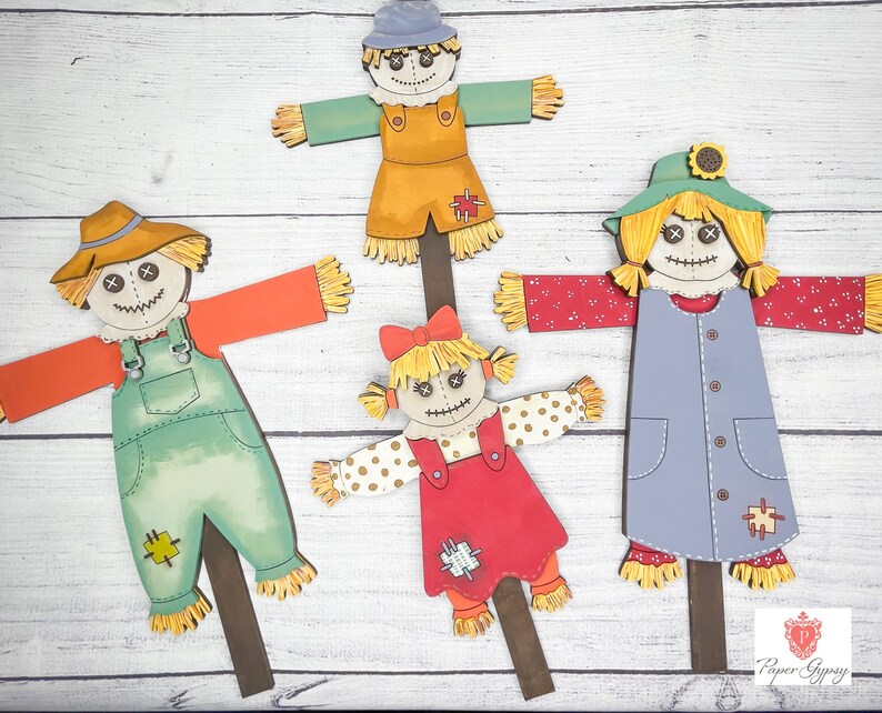 May include: Four colorful scarecrow figures with different clothing and hats. The scarecrows are made of paper and have a rustic, whimsical style. They are perfect for fall decorations.