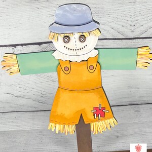 May include: A wooden scarecrow with a blue hat, white face, and orange overalls. The scarecrow has a red patch on the overalls and straw accents on the arms and legs.