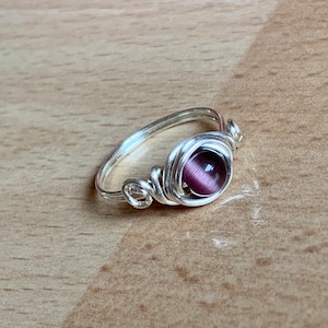 May include: A silver wire wrapped ring with a purple cat's eye stone.