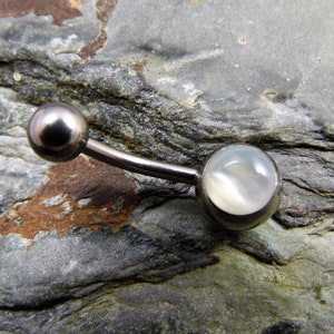 以下が含まれることがあります： 白い虹色の宝石が付いたシルバーのへそピアス