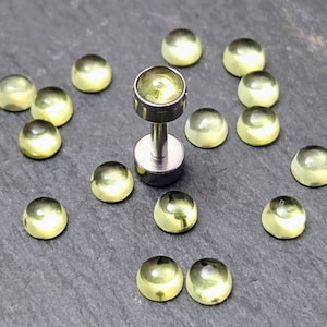May include: A collection of 15 small, round, translucent yellow glass cabochons, with one cabochon mounted on a silver post, a type of jewelry finding used for earrings or other body jewelry.