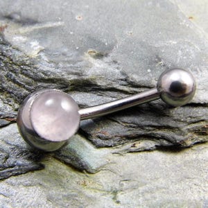 May include: A silver body piercing with a clear pink gem. The piercing is made of surgical steel and is designed for the belly button.