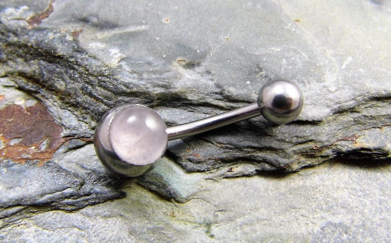 May include: A silver body piercing with a clear pink gem. The piercing is made of surgical steel and is designed for the belly button.