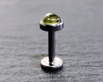 Könnte beinhalten: Ein silberner Barbell mit einem grünen Edelstein oben. Der Barbell ist ein Körperschmuck.