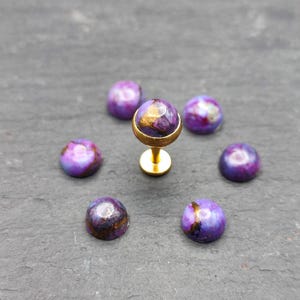 May include: A set of eight purple and gold gemstone studs with a gold post and a gold ball on top. The studs are arranged in a circle around the post.