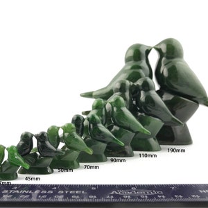Puede incluir: Un conjunto de 10 esculturas de p&aacute;jaros de jade verde en varios tama&ntilde;os, que van desde 37 mm hasta 190 mm. Los p&aacute;jaros est&aacute;n tallados en una pose de beso, con los p&aacute;jaros m&aacute;s grandes de pie sobre una base y los p&aacute;jaros m&aacute;s peque&ntilde;os posados ​​en sus espaldas. Las esculturas est&aacute;n dispuestas en una l&iacute;nea desde la m&aacute;s peque&ntilde;a hasta la m&aacute;s grande, con una regla debajo para referencia de tama&ntilde;o.