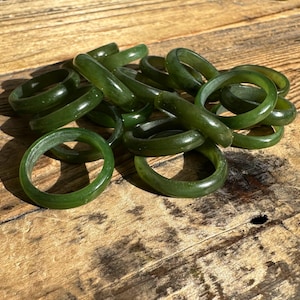 May include: A pile of green jade rings, each with a smooth, polished surface. The rings are stacked on top of each other, creating a visually appealing display.