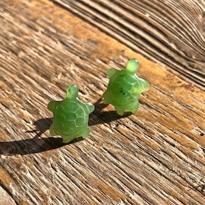 May include: A pair of green jade turtle earrings. The turtles are carved in detail and have a natural green colour.
