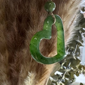 May include: A green jade heart pendant necklace with a simple design. The pendant is carved from a single piece of jade and has a smooth, polished finish.