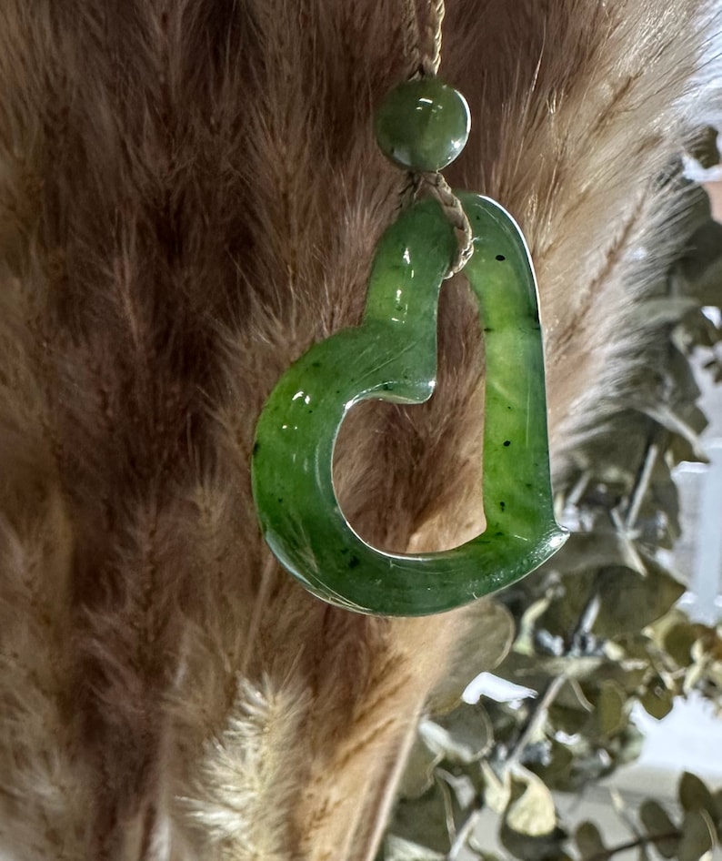May include: A green jade heart pendant necklace with a simple design. The pendant is carved from a single piece of jade and has a smooth, polished finish.