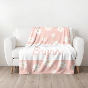 May include: A pink fleece blanket with a white daisy pattern and the name "Bryn" written in a cursive font.