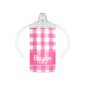 May include: A clear sippy cup with a pink and white gingham pattern. The cup has two clear handles and a clear lid with a spout. The name "Brynn" is printed in white script on a pink band.