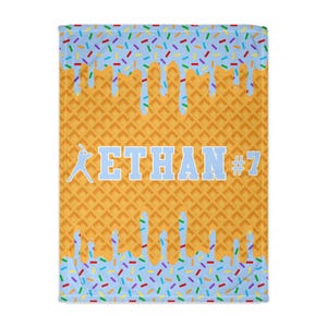 May include: A blue and yellow waffle cone blanket with blue icing and colorful sprinkles. The text "ETHAN #7" is printed on the blanket.