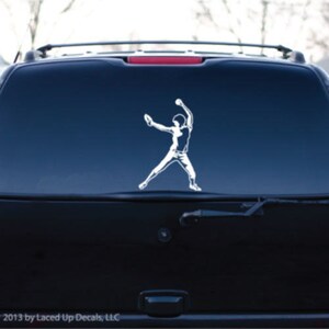 May include: White vinyl decal of a baseball pitcher in action, applied to the rear window of a black SUV. The decal shows the pitcher mid-throw, with arms extended. The copyright notice at the bottom reads "© 2013 by Laced Up Decals, LLC."