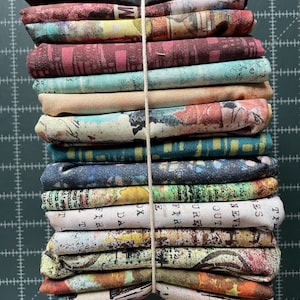 May include: A stack of 18 fabric squares with various patterns and colors, including black, brown, blue, green, yellow, and white. The fabric squares are tied together with a white string.
