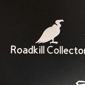May include: A black and white graphic design of a vulture with the text "Roadkill Collector" below it.