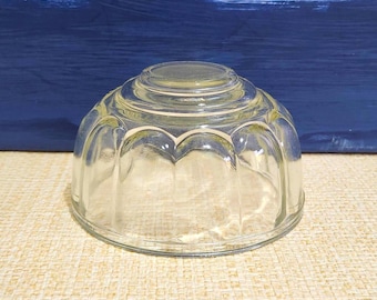 May include: A clear glass dessert mold with a fluted design. The mold is round and has a domed top.