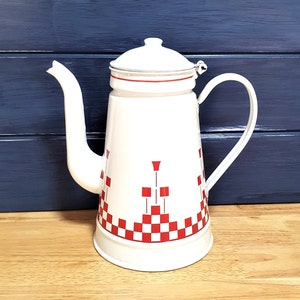 May include: White enamel coffee pot with a red chequered pattern around the base and red accents. The pot has a long spout, a curved handle, and a lid. The design includes red squares and rectangles.