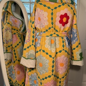 May include: A yellow quilted robe with a green diamond pattern and floral appliques. The robe has a hood and a tie belt.