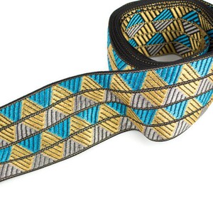 May include: A blue, gold, and silver patterned trim with a geometric design. The trim is rolled up and ready to be used for sewing or crafting projects.