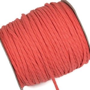May include: A spool of coral red cotton cord. The cord is twisted and has a textured surface.