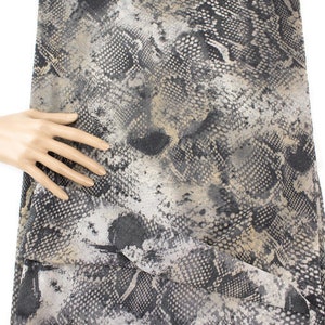 May include: A black and beige fabric with a snakeskin pattern.