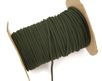 May include: A spool of dark green cord, wound tightly on a cardboard spool. The cord is smooth and appears to be made of a synthetic material.