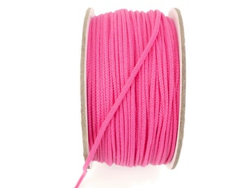 May include: A spool of pink cord, wound tightly on a cardboard spool. The cord is smooth and appears to be made of cotton.