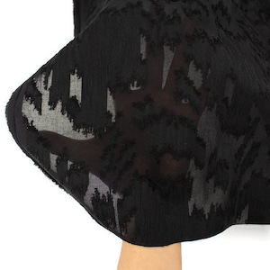 May include: Black sheer fabric with a textured, abstract pattern. The fabric is soft and flowy, and the pattern is subtle and elegant.