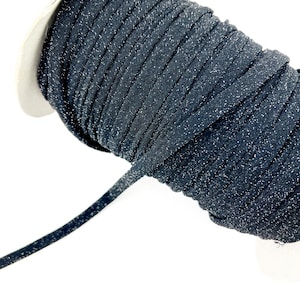 May include: A spool of dark blue elastic cord with a glittery, speckled appearance. The cord is tightly wound, with a length of the cord extending from the spool. The background is white.