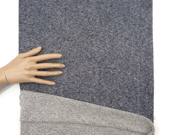 May include: A section of gray fabric with a textured surface, partially folded over to reveal a lighter gray, woven underside. A mannequin hand rests on the top fabric, with a white background.