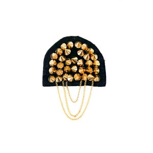 May include: A black fabric patch with gold-colored metal studs and a chain hanging from the bottom.