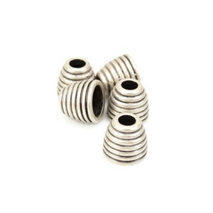 May include: Five silver metal bead caps with a ridged design. The caps are round with a hole in the center.