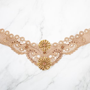 May include: Gold lace trim with a floral design and beaded accents. The trim is perfect for adding a touch of elegance to any project.