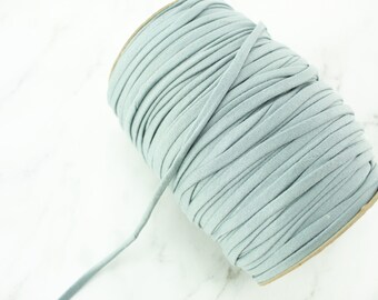 May include: A spool of light blue cord or string. The cord is wound tightly around a cardboard core.
