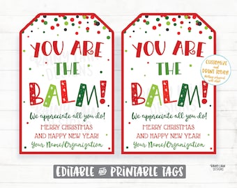 Pode incluir: Duas etiquetas de presente imprimíveis com fundo de bolinhas vermelhas e verdes. As etiquetas apresentam o texto "You are the balm!" em letras vermelhas, verdes e brancas com um padrão de estrelas. O texto "We appreciate all you do! Merry Christmas and Happy New Year! Your Name/Organization" está impresso abaixo do texto principal.