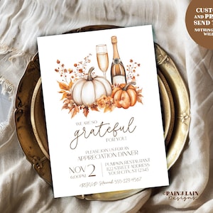 May include: A white invitation card with a fall theme, featuring pumpkins, champagne, and floral accents. The text reads "We are so grateful for you!" and includes event details. The card is on a decorative plate.