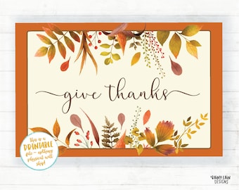 Könnte beinhalten: Druckbarer Thanksgiving-Schilder mit weißem Hintergrund und orangefarbenem Rand. Das Schild zeigt ein Aquarelldesign aus Herbstblättern in Orange-, Rot- und Gelbtönen. Der Text "give thanks" ist in einer kursivschriftlichen Schriftart geschrieben.