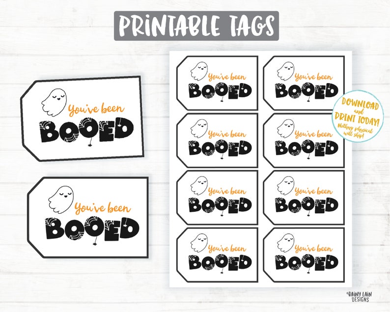 May include: Printable Halloween gift tags featuring a ghost with the text "You've been Booed" in black and orange lettering. The tags are designed to be printed and used for Halloween gift giving.